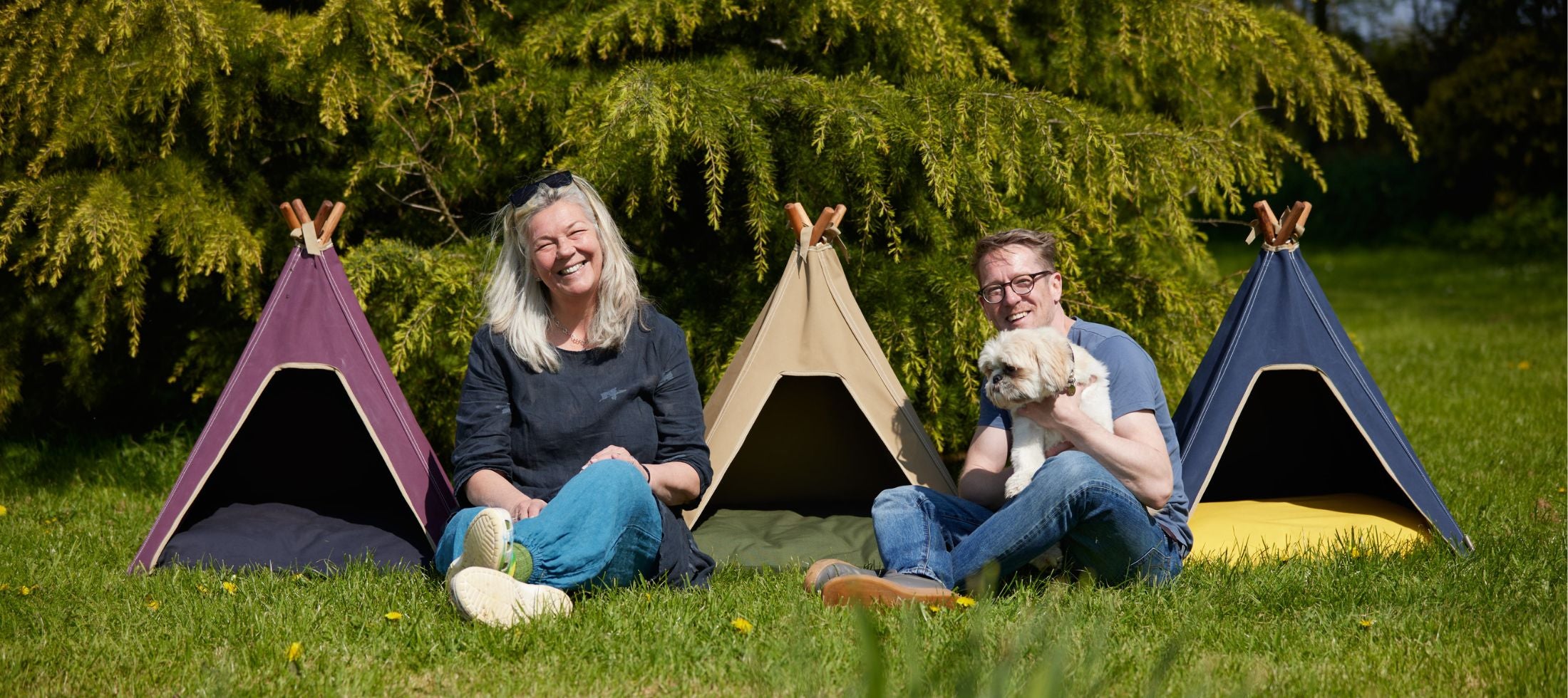 Pooch and Paws founders. Sitting by dog teepees outside, garden setting 